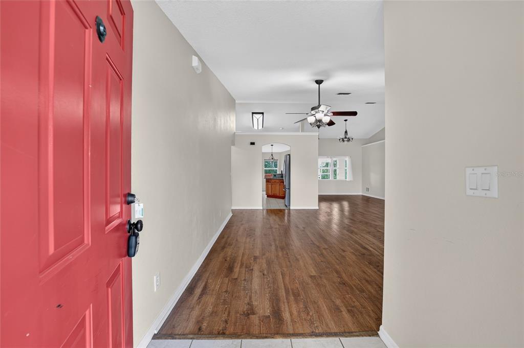 A red front door opens into a living area with wood-look flooring and vaulted ceilings — 10384 SW 41ST COURT, OCALA, FL