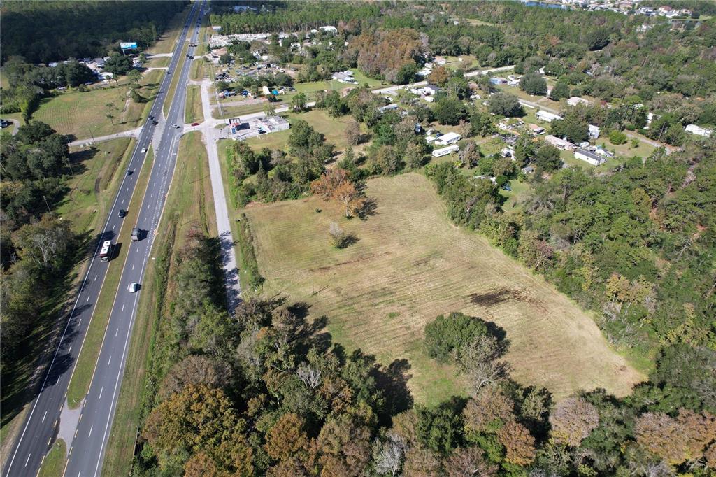 An aerial view shows a large, cleared rectangular lot adjacent to a multi-lane highway — 18049 OLD CHENEY HWY, ORLANDO, FL
