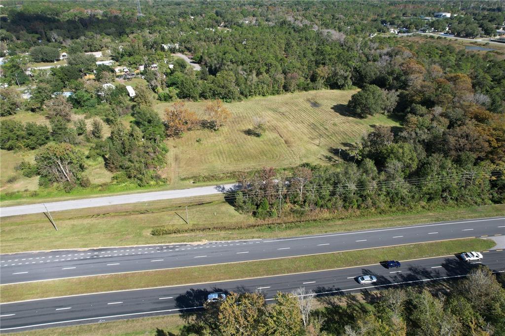 An aerial view shows a vacant grassy lot situated next to a multi-lane highway — 18049 OLD CHENEY HWY, ORLANDO, FL
