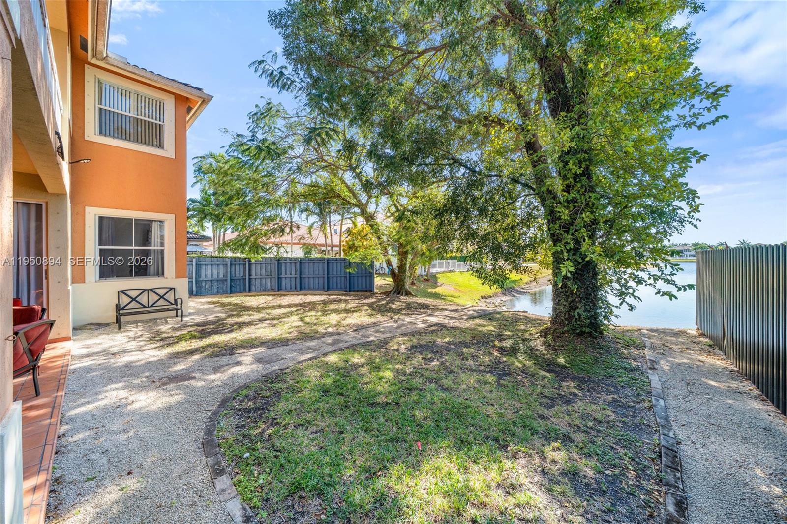 A view of a calm lake surrounded by grassy banks and residential houses under blue skies — 16062 SW 43rd Ter, Miami FL 33185, MIAMI, FL