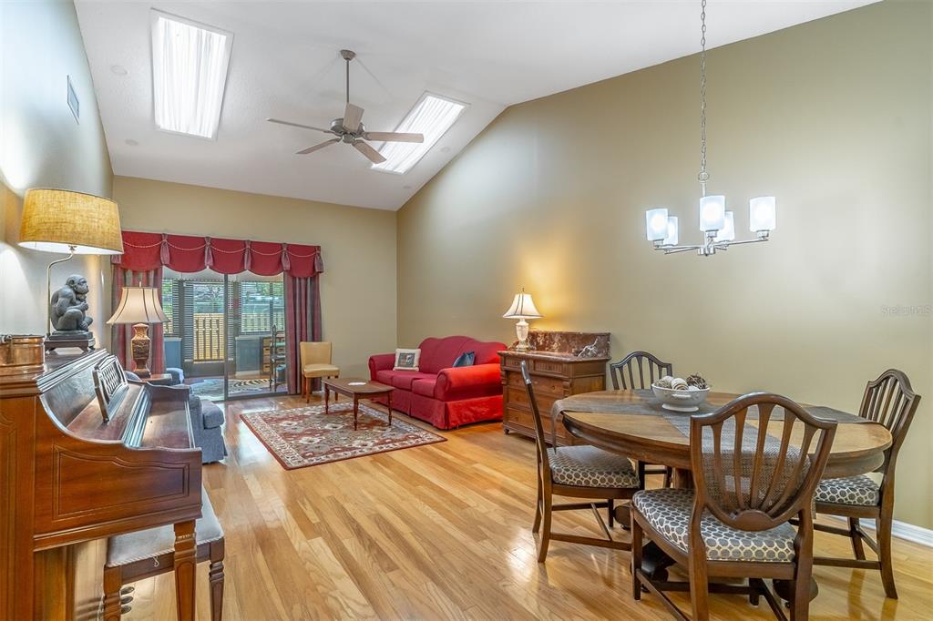 A living and dining area with hardwood floors, vaulted ceilings, and a red sofa — 2503 TAHOE CIRCLE UNIT 2503, WINTER PARK, FL