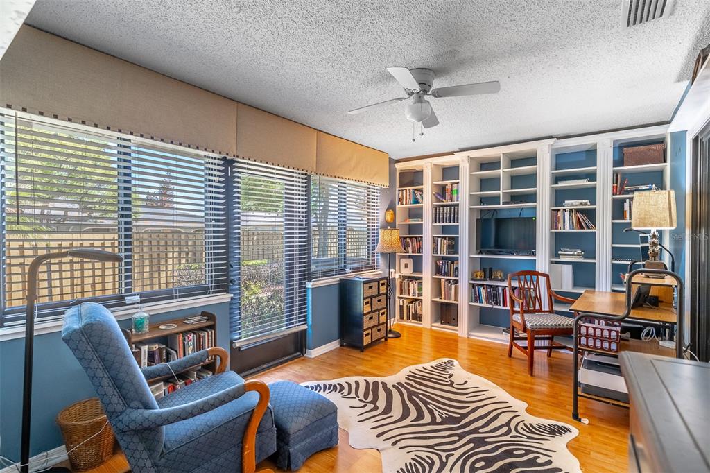A home office with blue walls, built-in white bookshelves, a zebra-print rug, and hardwood floors — 2503 TAHOE CIRCLE UNIT 2503, WINTER PARK, FL