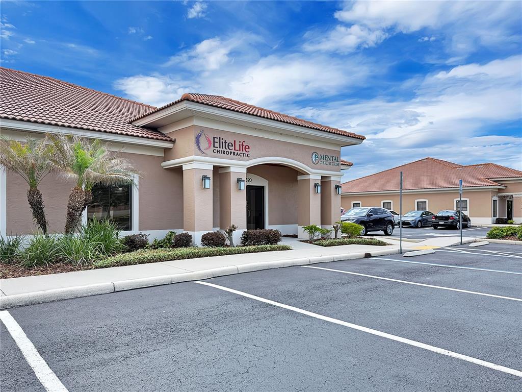 The exterior of a commercial building features a tan facade, tiled roof, and parking lot — 2320 NORTH BOULEVARD W UNIT A, DAVENPORT, FL