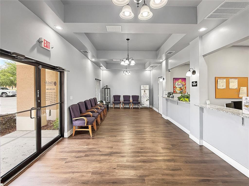 A waiting room features wood-look flooring, purple chairs, a reception desk, and two chandeliers — 2320 NORTH BOULEVARD W UNIT A, DAVENPORT, FL