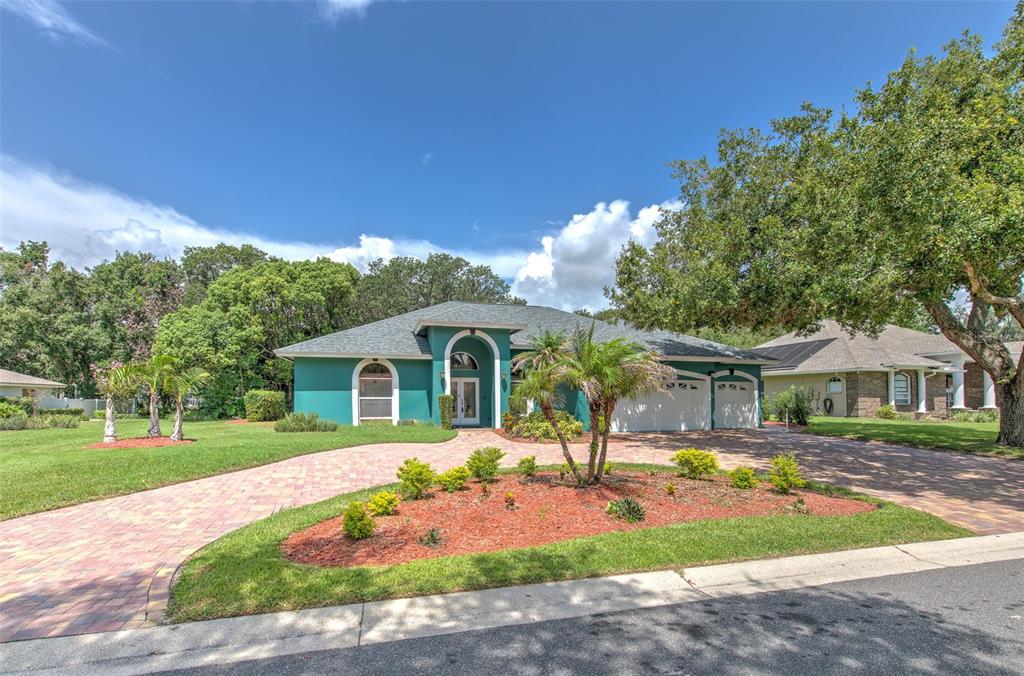 A teal single-story house with a brick paver driveway and a landscaped front yard — 2809 BARRET AVENUE, PLANT CITY, FL