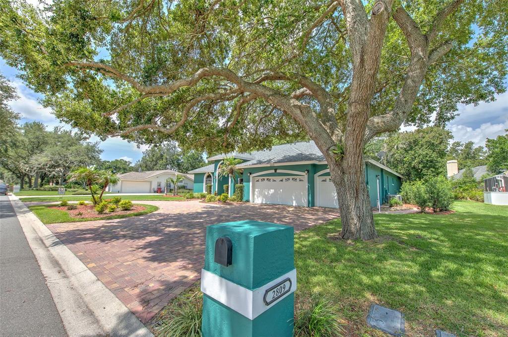 A teal house with a brick driveway and a large oak tree in the front yard — 2809 BARRET AVENUE, PLANT CITY, FL