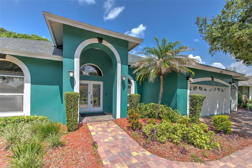 A teal house features a white arched entryway, a paver walkway, and a palm tree — 2809 BARRET AVENUE, PLANT CITY, FL