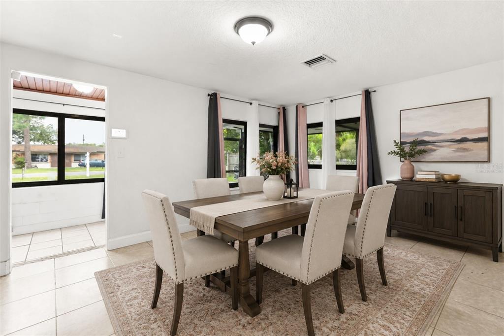A dining room features a wooden table with six upholstered chairs on a patterned rug — 2617 S LAUREL AVENUE, SANFORD, FL