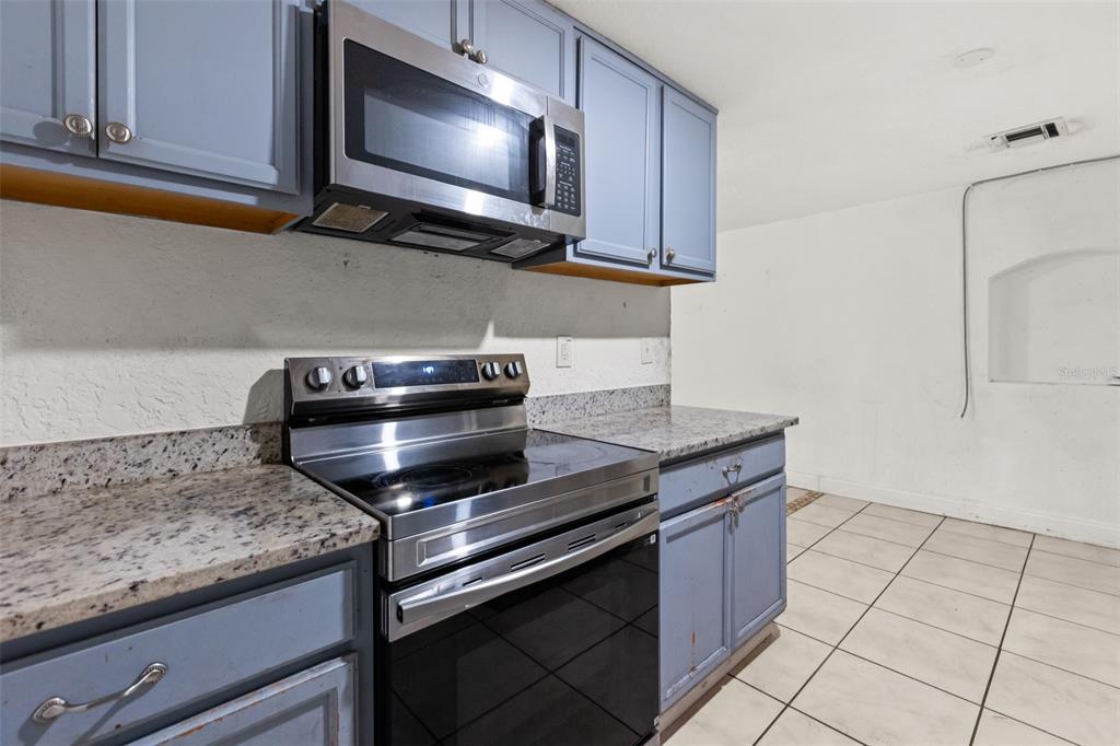 A kitchen features blue cabinets, granite countertops, and stainless steel appliances — 2617 S LAUREL AVENUE, SANFORD, FL