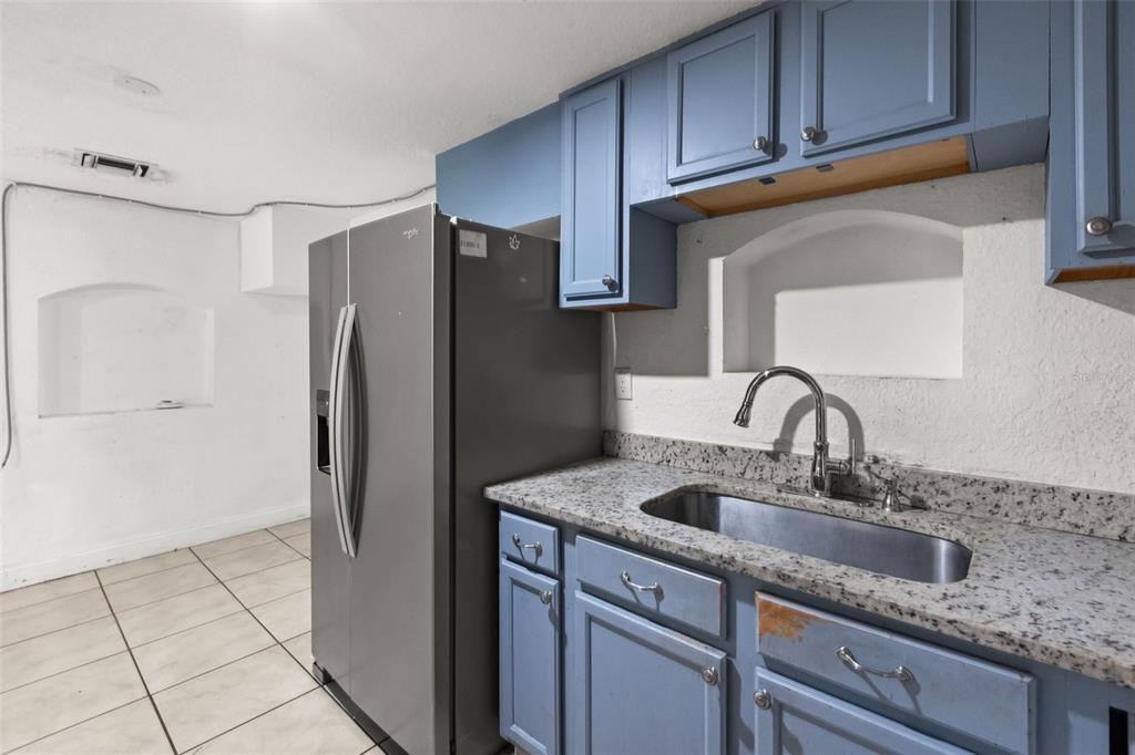 A kitchen features blue cabinets, a granite countertop, a stainless steel sink, and a refrigerator — 2617 S LAUREL AVENUE, SANFORD, FL