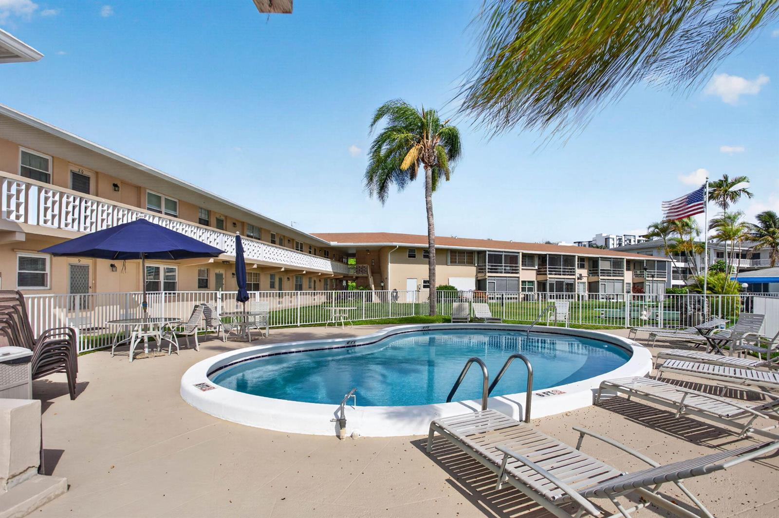 An outdoor swimming pool surrounded by lounge chairs and a multi-story apartment building — 298 SE 6th Avenue # 9, Pompano Beach FL 33060, POMPANO BEACH, FL