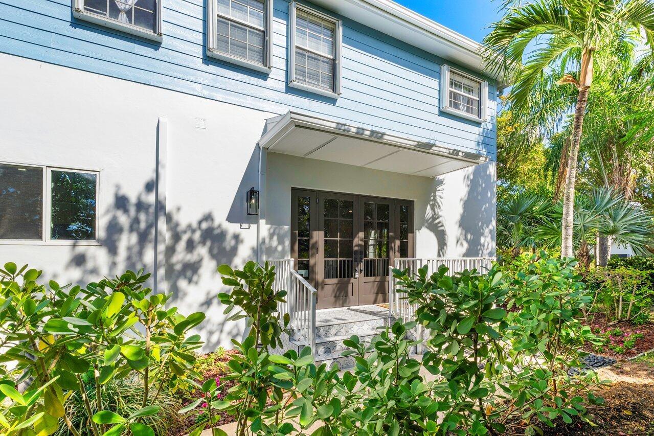 The exterior of a light blue two-story house features a covered entryway with double doors — 1920 Spanish Trail, Delray Beach FL 33483, DELRAY BEACH, FL