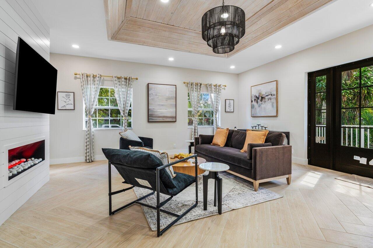A living room features a fireplace, dark furniture, a coffered ceiling, and light wood flooring — 1920 Spanish Trail, Delray Beach FL 33483, DELRAY BEACH, FL