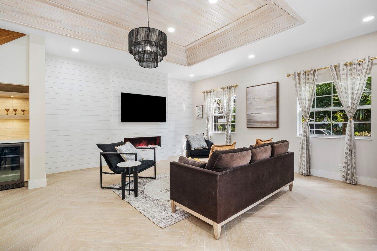 A living room features a coffered wood ceiling, a fireplace, and a dark sofa — 1920 Spanish Trail, Delray Beach FL 33483, DELRAY BEACH, FL