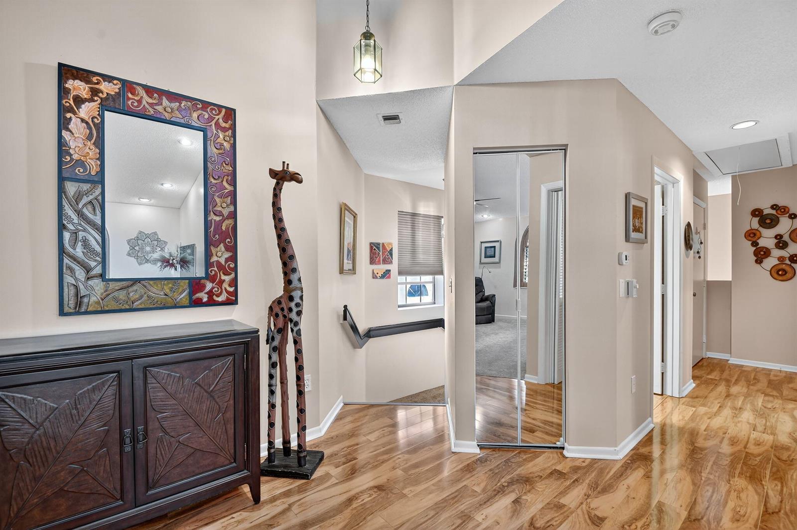 An entryway features hardwood flooring, a decorative mirror, a giraffe statue, and a mirrored closet — 5187 Europa Drive # P, Boynton Beach FL 33437, BOYNTON BEACH, FL