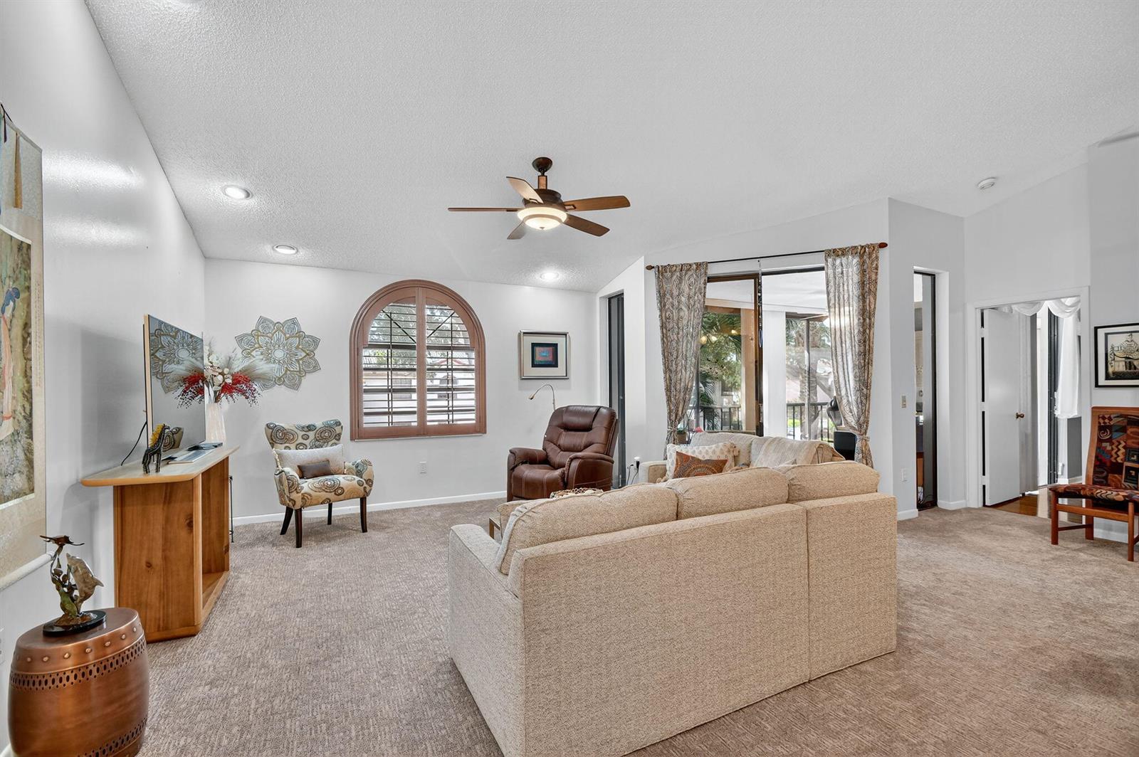 A living room with beige carpet, a sectional sofa, a brown recliner, and an arched window — 5187 Europa Drive # P, Boynton Beach FL 33437, BOYNTON BEACH, FL