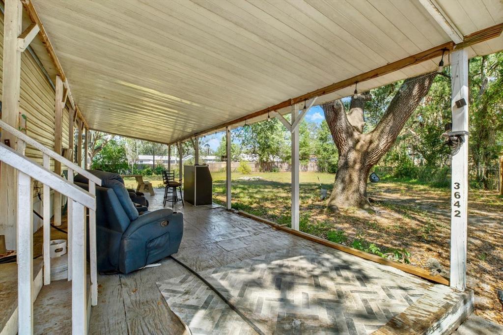 A covered patio features a blue recliner, a bar, and a patterned tiled floor — 3642 KALMAN DRIVE, ZEPHYRHILLS, FL