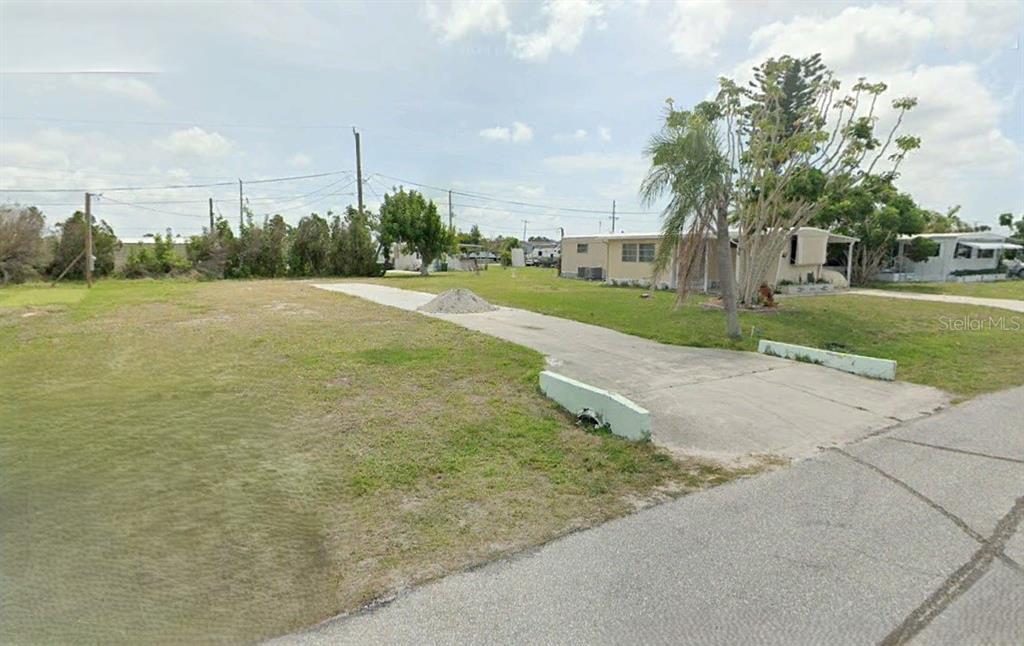 A vacant grassy lot features a concrete driveway and a small pile of gravel — 1403 SEAGULL DRIVE, ENGLEWOOD, FL