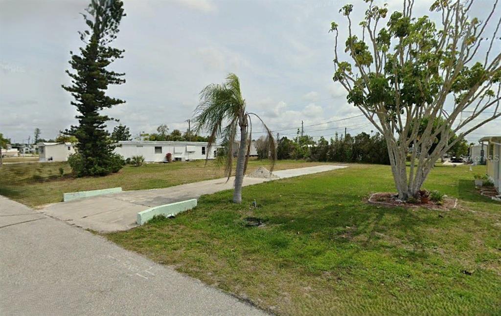 A vacant residential lot features a concrete driveway, a palm tree, and a large tree — 1403 SEAGULL DRIVE, ENGLEWOOD, FL