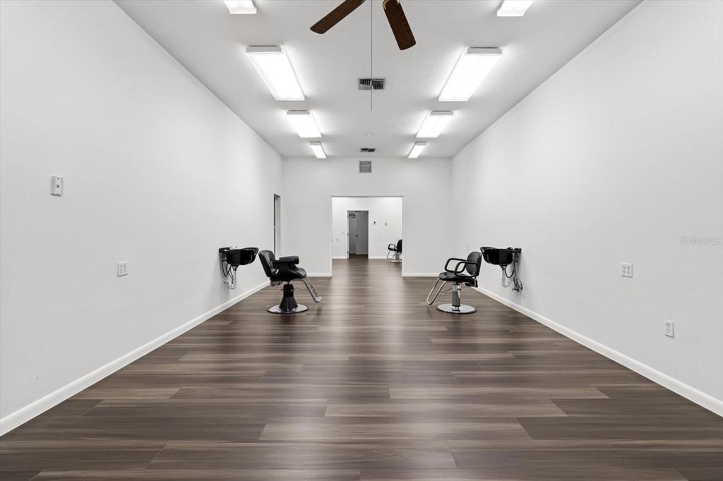 A long, white-walled salon room features two shampoo stations and dark wood-look flooring — 3438 N CITRUS AVENUE, CRYSTAL RIVER, FL