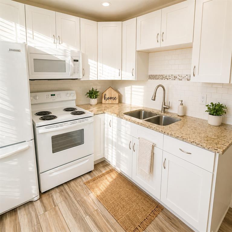 A kitchen features white cabinets, granite countertops, a white stove, and a stainless steel sink — 2501 HARN BOULEVARD UNIT H27, CLEARWATER, FL