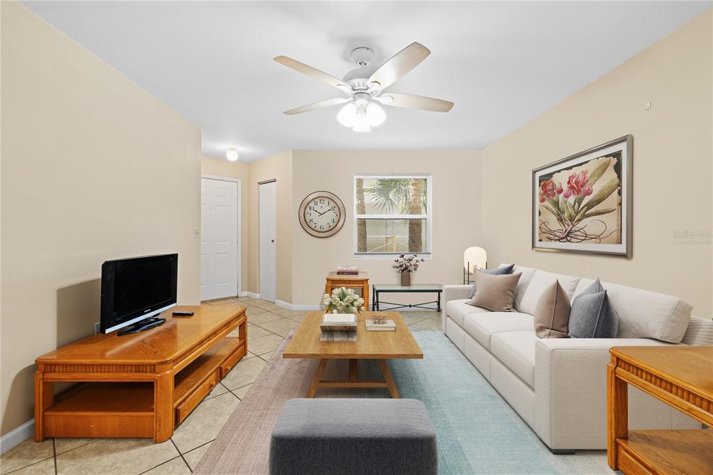 A living room features a white sofa, a wooden coffee table, and a ceiling fan — 3032 PARKWAY BOULEVARD UNIT 208, KISSIMMEE, FL