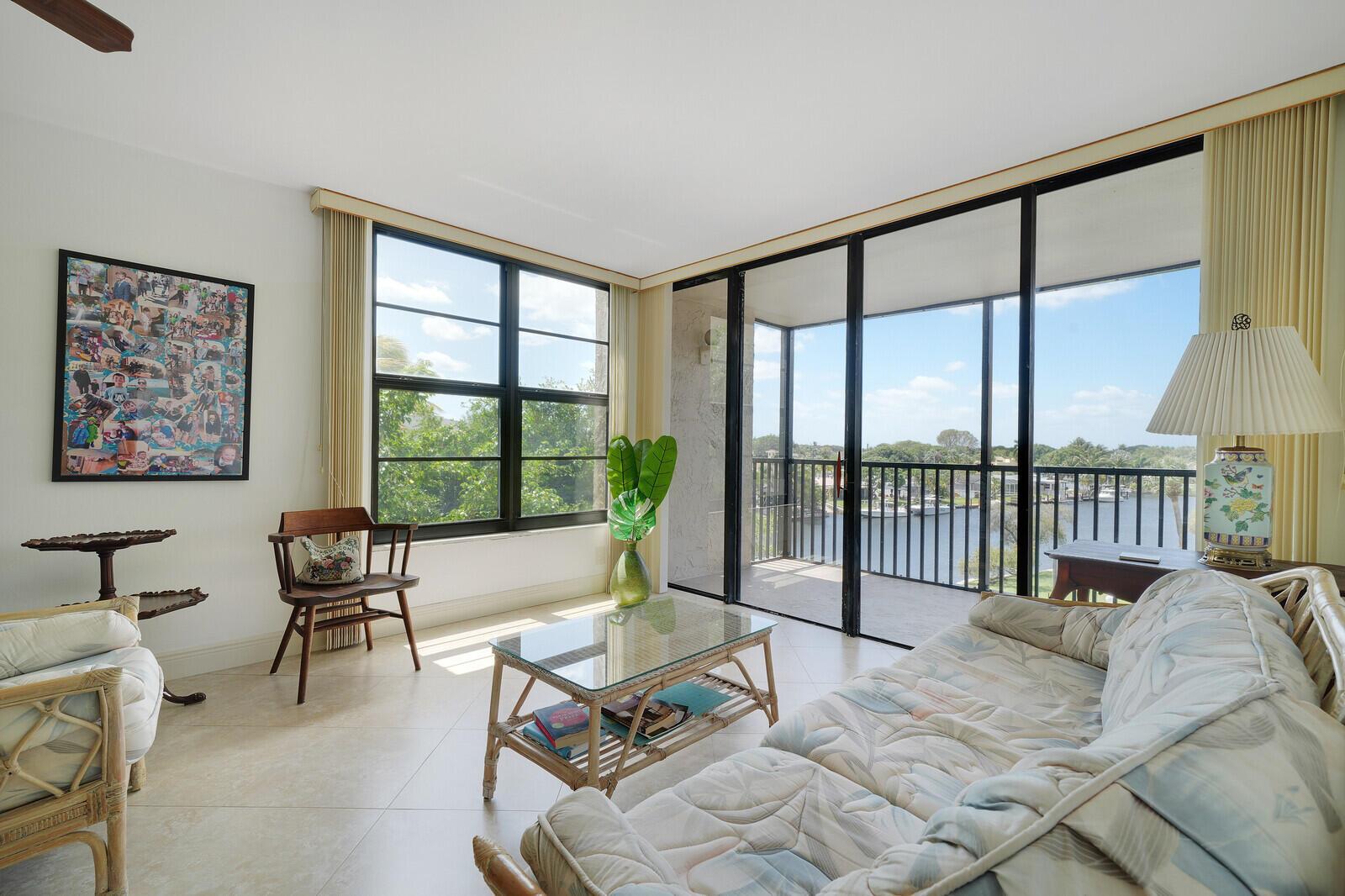 A living room features tile floors, a glass coffee table, and a balcony overlooking water — 8 Royal Palm Way # 401, Boca Raton FL 33432, BOCA RATON, FL