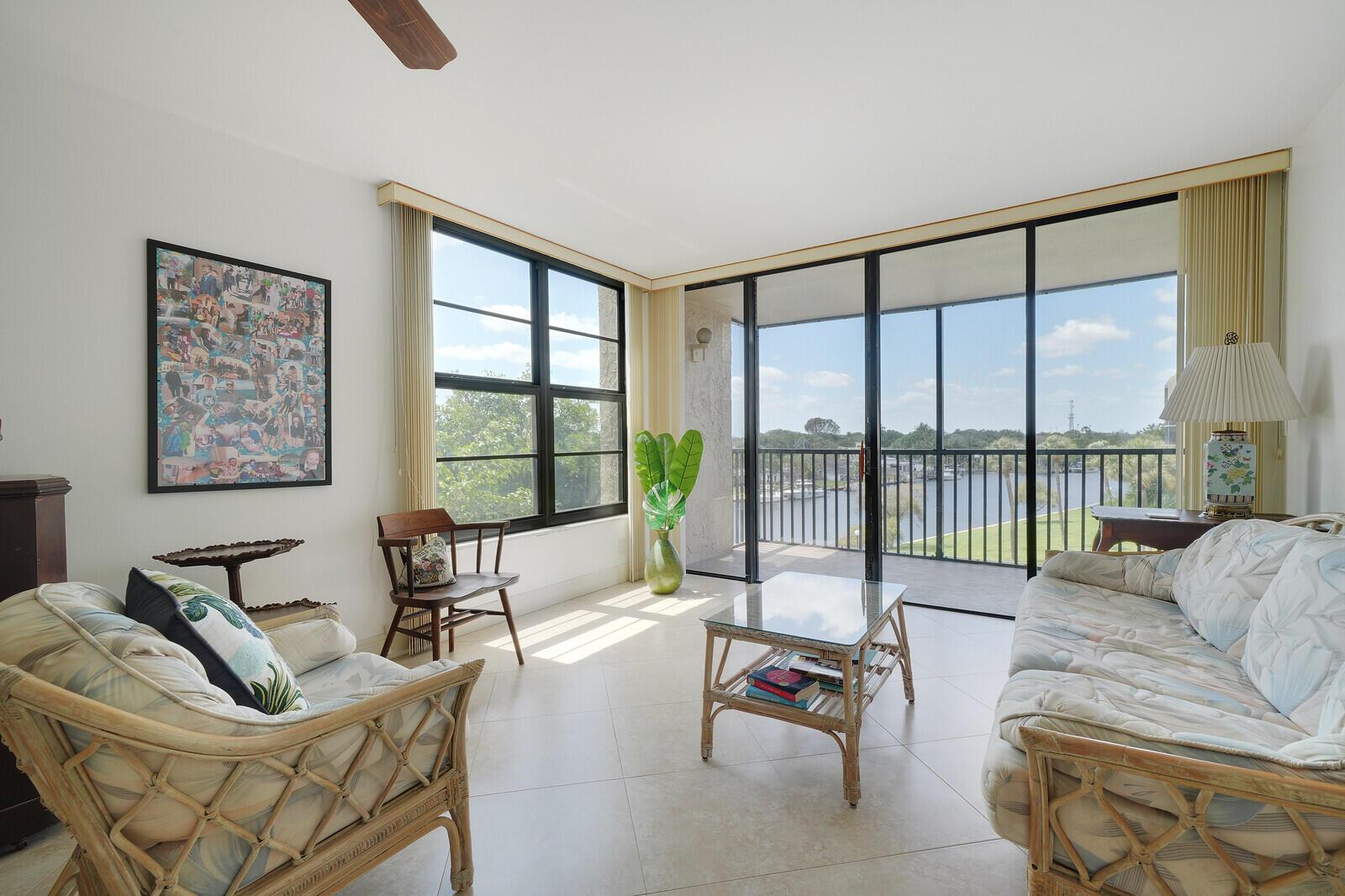 A living room with wicker furniture, tile floors, and a balcony overlooking a waterway — 8 Royal Palm Way # 401, Boca Raton FL 33432, BOCA RATON, FL