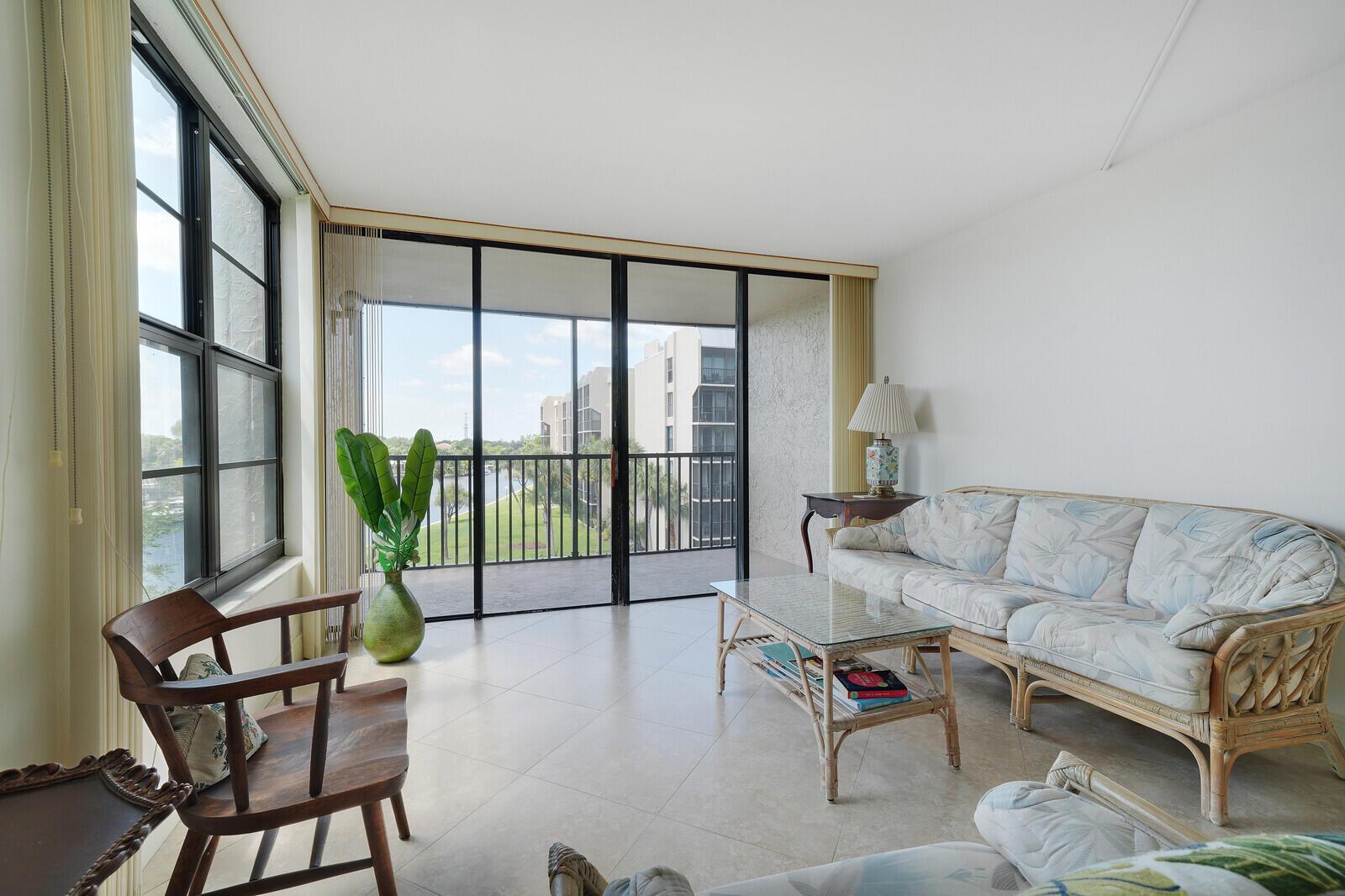 A living room with tile floors, a rattan sofa, and a balcony overlooking a waterway — 8 Royal Palm Way # 401, Boca Raton FL 33432, BOCA RATON, FL
