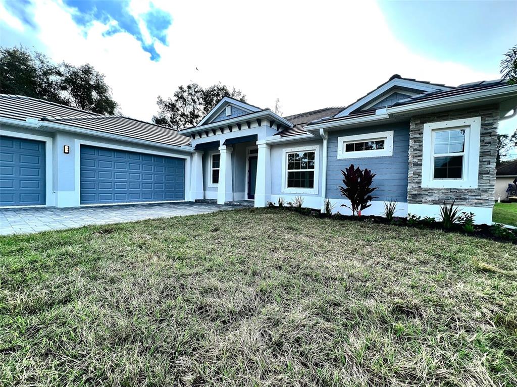 A single-story house with a blue garage, stone accents, and a paved driveway — 3120 WENONA DRIVE, NORTH PORT, FL