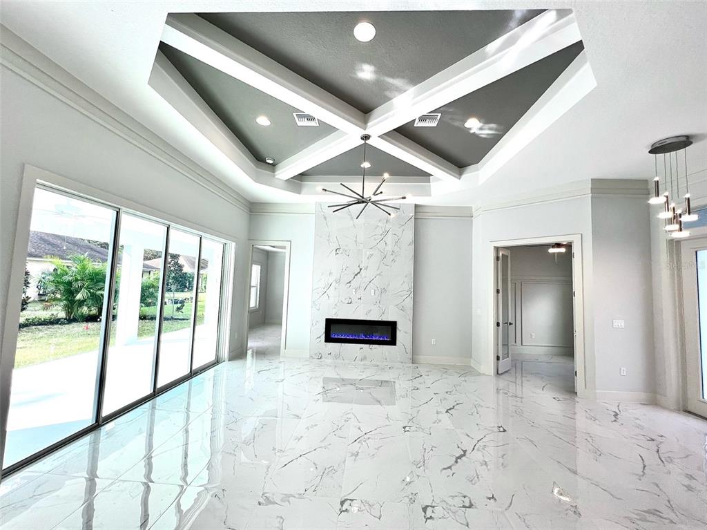 A living room features a marble fireplace, coffered ceiling, and large sliding glass doors — 3120 WENONA DRIVE, NORTH PORT, FL