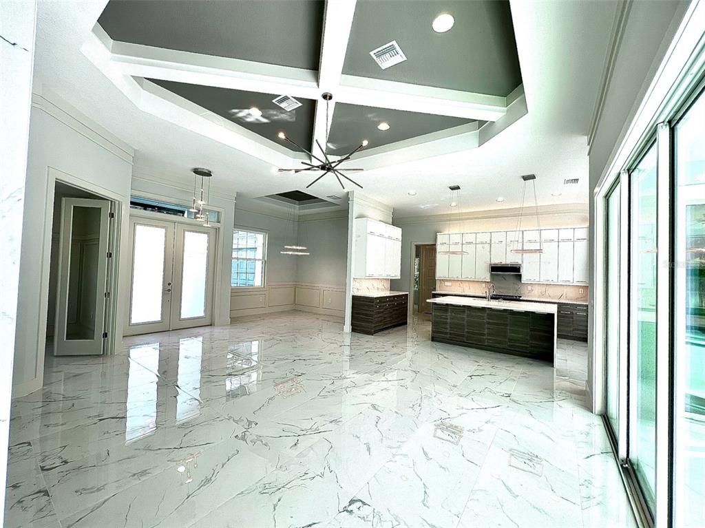 A spacious open-concept kitchen and living area features a coffered ceiling and marble tile flooring — 3120 WENONA DRIVE, NORTH PORT, FL