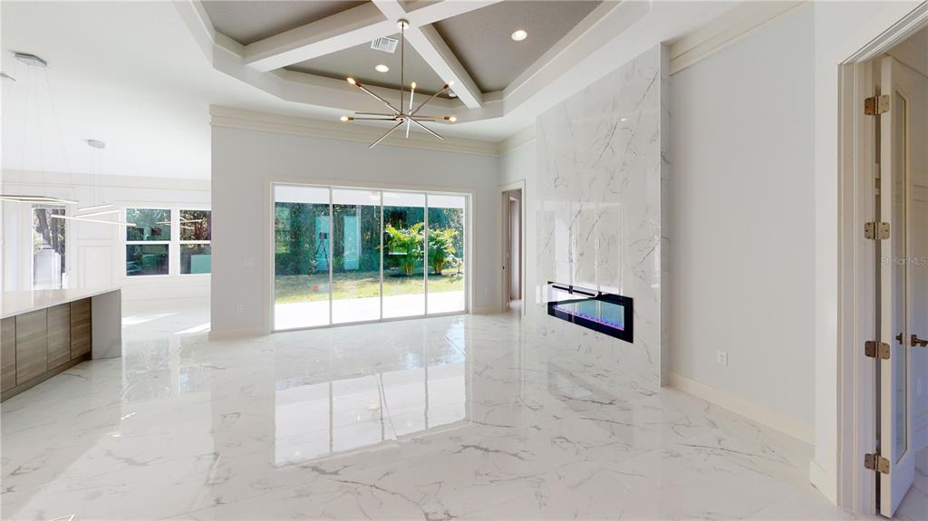 A modern living room features a marble fireplace, tile flooring, and a coffered ceiling — 3120 WENONA DRIVE, NORTH PORT, FL