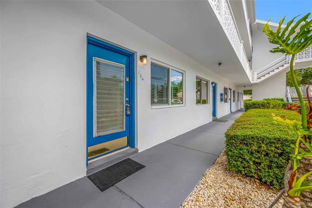 A ground-level apartment entrance with a blue door and a welcome mat on a walkway — 8075 112TH STREET UNIT 104, SEMINOLE, FL