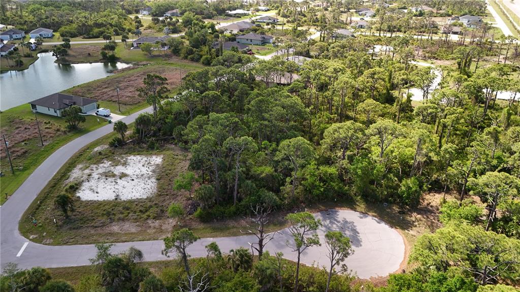 An aerial view shows a vacant residential lot with trees and a cul-de-sac road — 103 HAWK DRIVE, ROTONDA WEST, FL