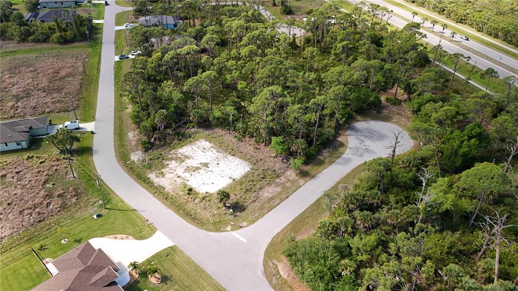 An aerial view shows a vacant, wooded residential lot situated at the end of a cul-de-sac — 103 HAWK DRIVE, ROTONDA WEST, FL
