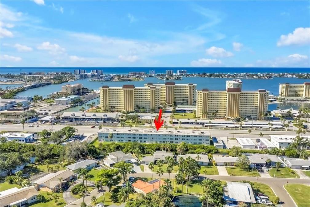 An aerial view shows a multi-story apartment building with a red arrow pointing toward it — 4455 DUHME ROAD UNIT 103, ST PETERSBURG, FL