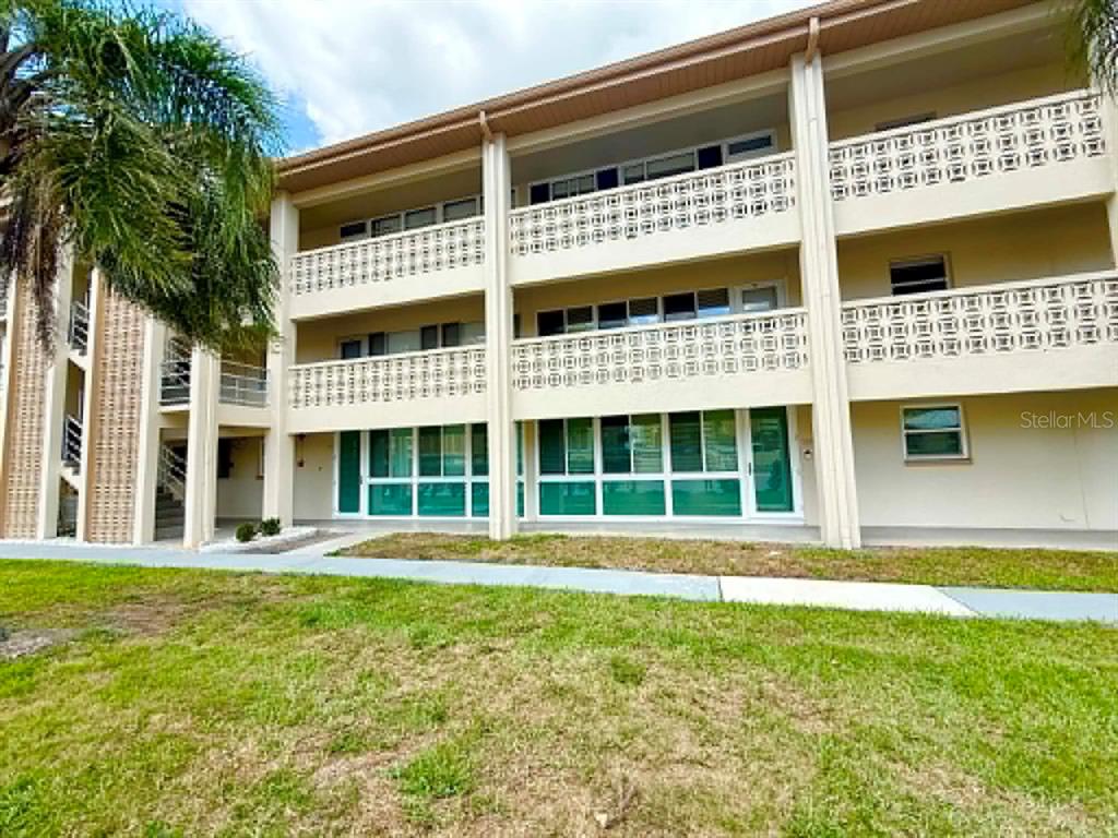 A three-story apartment building features exterior balconies with decorative concrete breeze block railings — 4455 DUHME ROAD UNIT 103, ST PETERSBURG, FL