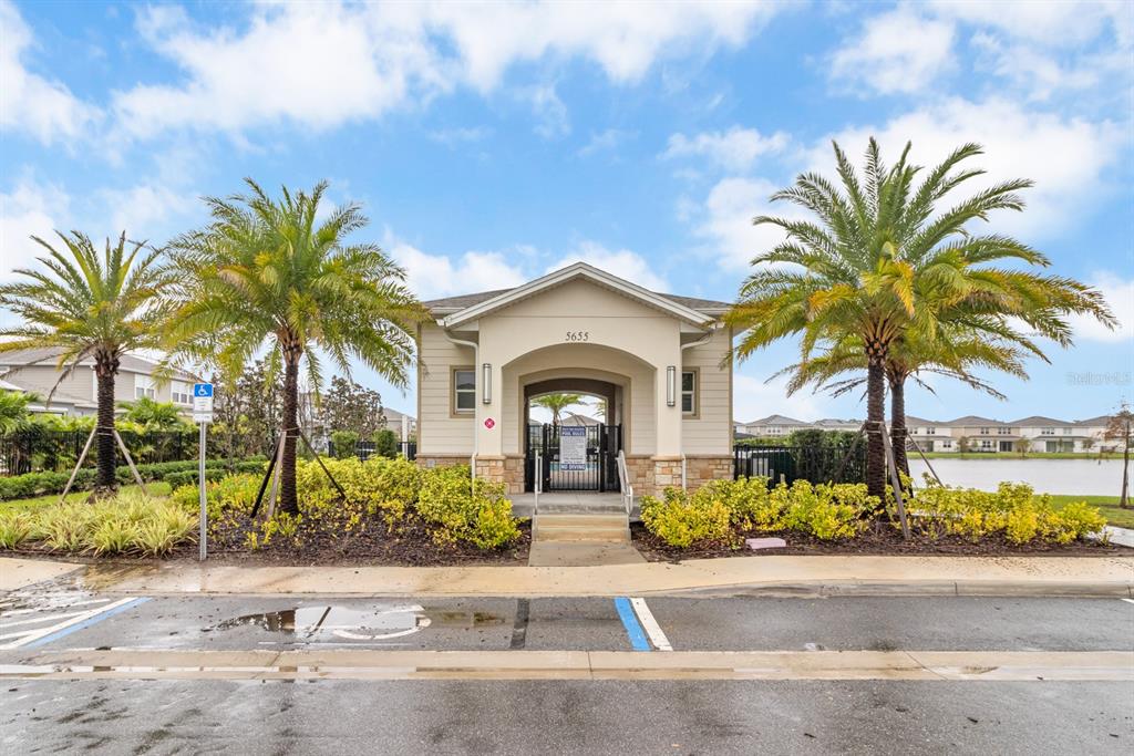 A beige community building entrance features a gated walkway flanked by two large palm trees — 5674 ARBORVISTA DRIVE, ST CLOUD, FL