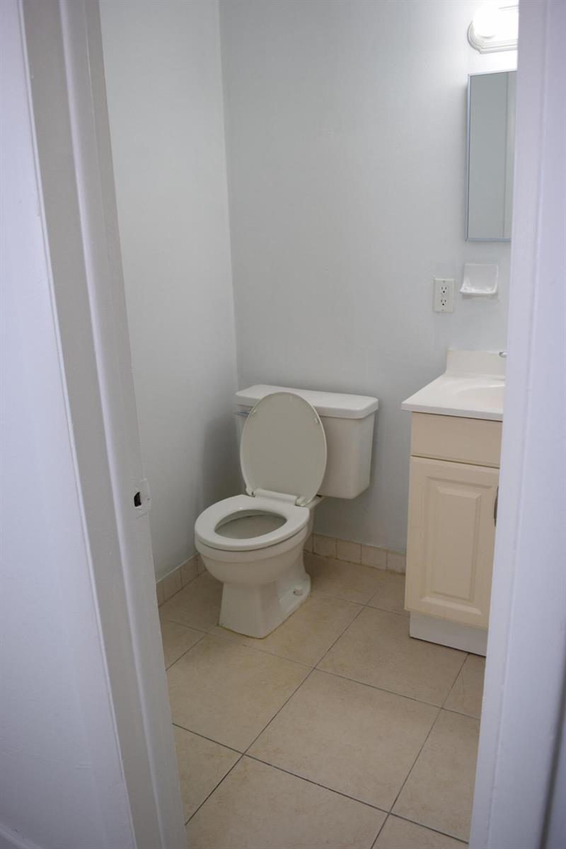 A small bathroom features a white toilet, a vanity with a sink, and tiled flooring — 151 SE 6th Avenue Apt 14, Pompano Beach FL 33060, POMPANO BEACH, FL
