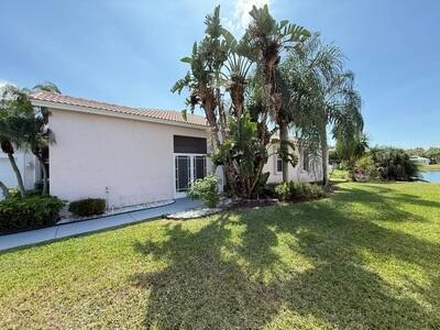 A light-colored house exterior features a screened patio area surrounded by palm trees and grass — 10839 Madison Drive, Boynton Beach FL 33437, BOYNTON BEACH, FL