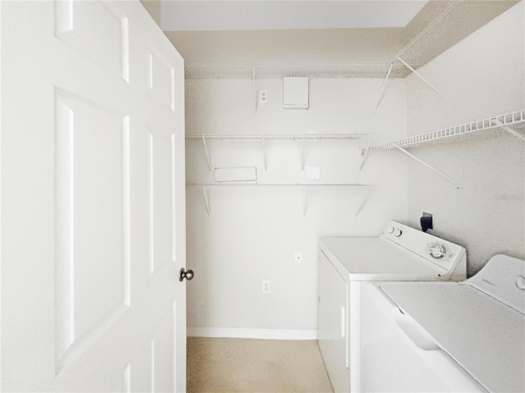 A laundry closet features white appliances, wire shelving, and a white door — 10205 COURTNEY PALMS BOULEVARD UNIT 101, TAMPA, FL