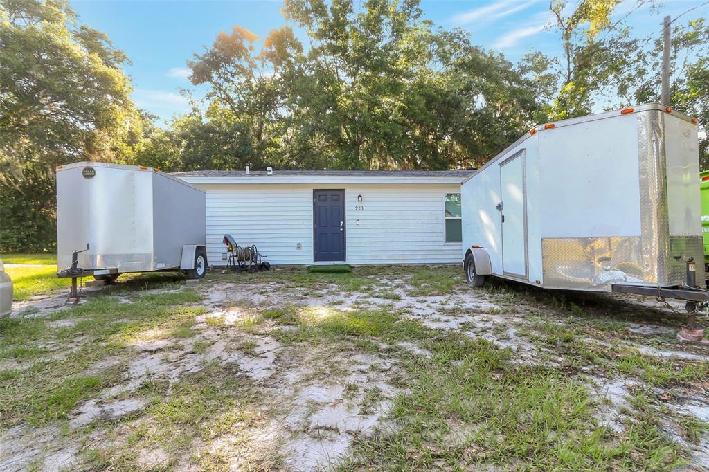 A single-story white house with a dark blue front door sits between two utility trailers — 923 OXFORD STREET, LONGWOOD, FL
