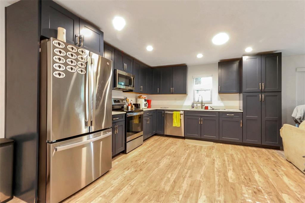 A kitchen features dark blue cabinets, stainless steel appliances, and light wood-look flooring — 923 OXFORD STREET, LONGWOOD, FL