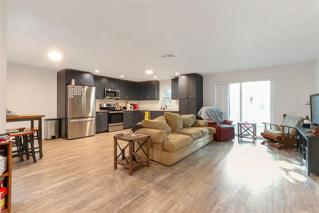 An open-concept living room and kitchen feature dark cabinets, stainless steel appliances, and wood flooring — 923 OXFORD STREET, LONGWOOD, FL