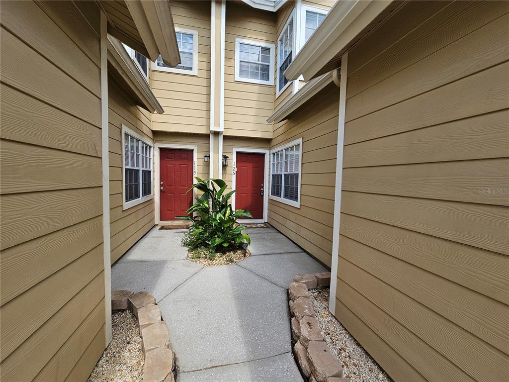 A tan townhouse exterior features red front doors and a sunset sky in the background — 125 AUSTRALIAN WAY, DAVENPORT, FL
