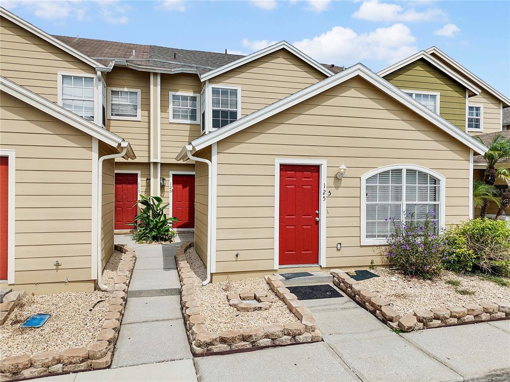 A two-story tan apartment building with red doors and a parking lot in front — 125 AUSTRALIAN WAY, DAVENPORT, FL