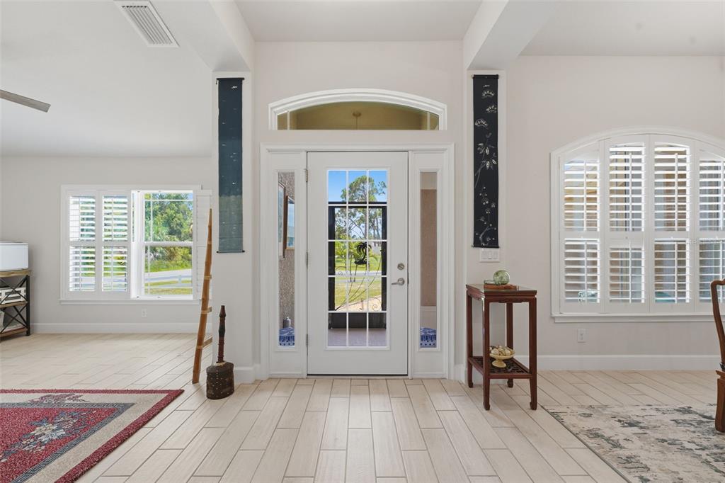A bright entryway features a white front door with sidelights, tile flooring, and plantation shutters — 2602 YAMADA LANE, NORTH PORT, FL