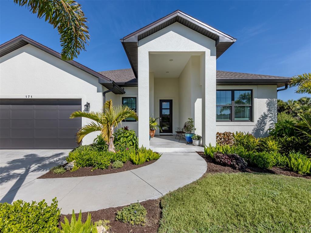 A single-story house with a white exterior, dark garage door, and a covered front entryway — 171 SPRING DRIVE, ROTONDA WEST, FL