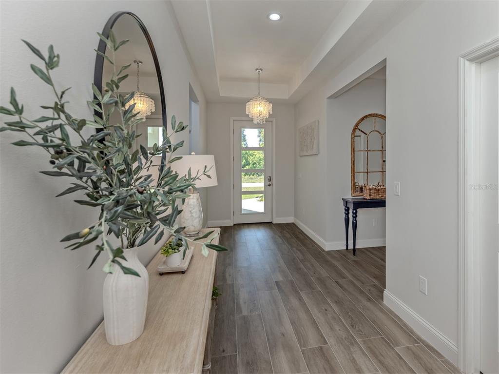 A bright entryway features a wood-look tile floor, a tray ceiling, and a glass-paneled door — 171 SPRING DRIVE, ROTONDA WEST, FL